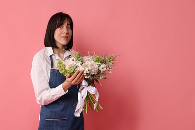Photo of Florist with beautiful bouquet of flowers on pink background, space for text