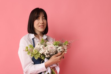 Photo of Florist with beautiful bouquet of flowers on pink background, space for text