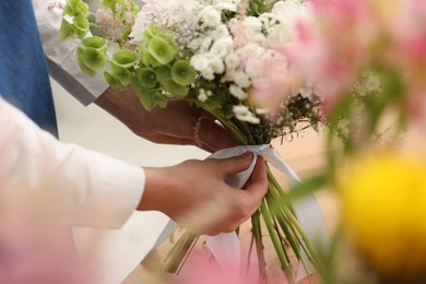 Photo of Florist making bouquet of flowers indoors, closeup