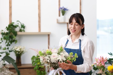 Photo of Florist with beautiful bouquet of flowers indoors