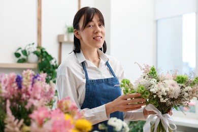 Photo of Florist with beautiful bouquet of flowers indoors