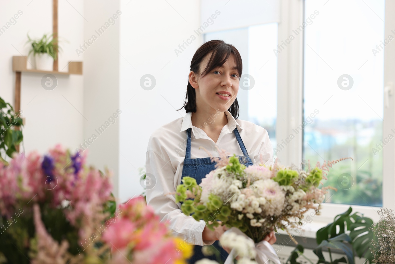 Photo of Florist with beautiful bouquet of flowers indoors