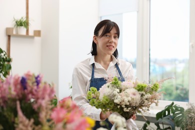 Photo of Florist with beautiful bouquet of flowers indoors