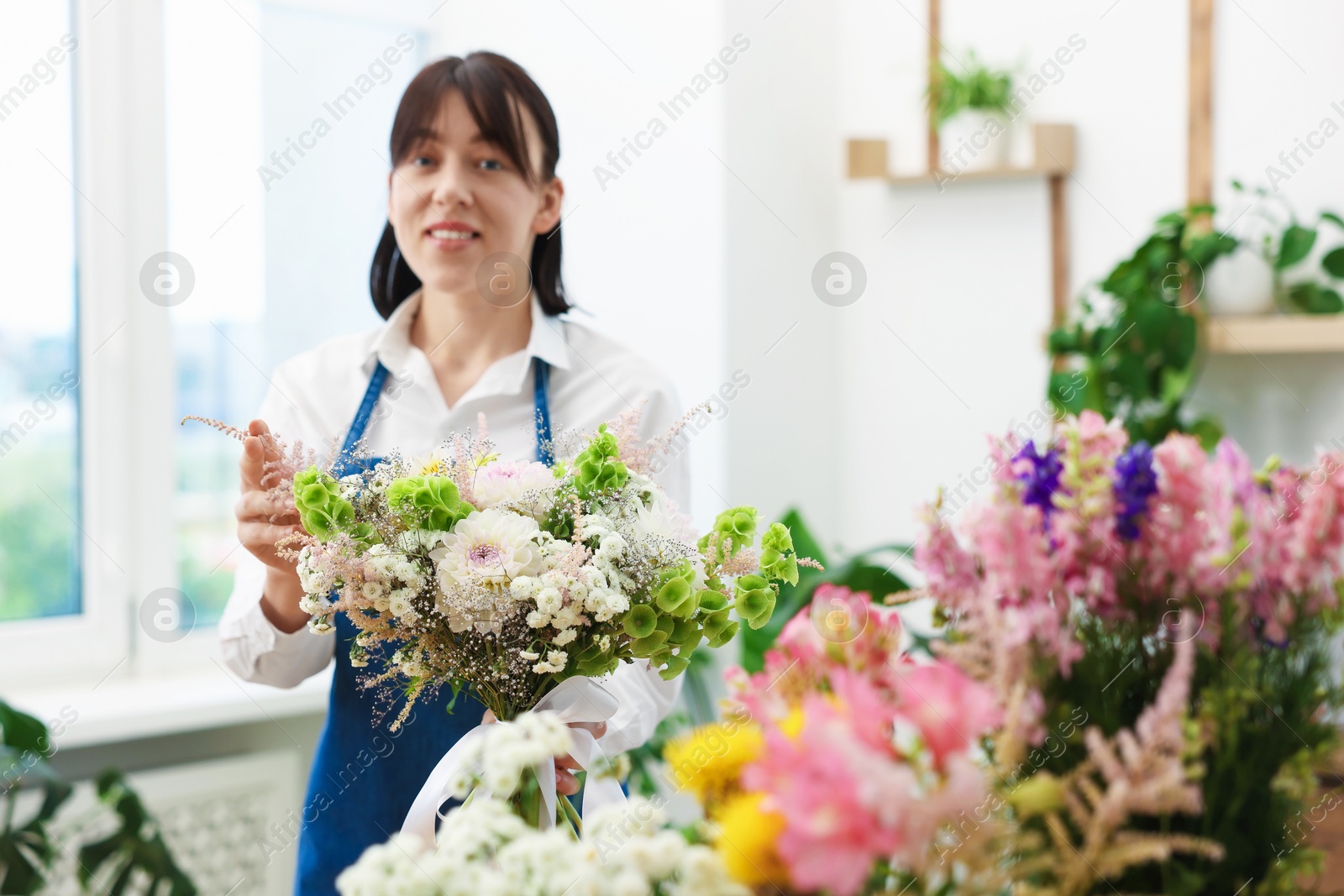 Photo of Florist with beautiful bouquet of flowers indoors, selective focus