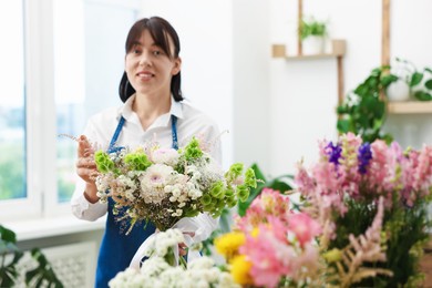 Photo of Florist with beautiful bouquet of flowers indoors, selective focus