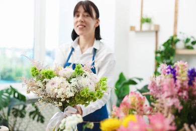 Photo of Florist with beautiful bouquet of flowers indoors, selective focus