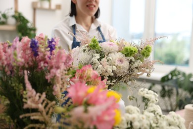 Photo of Florist with beautiful bouquet of flowers indoors, selective focus