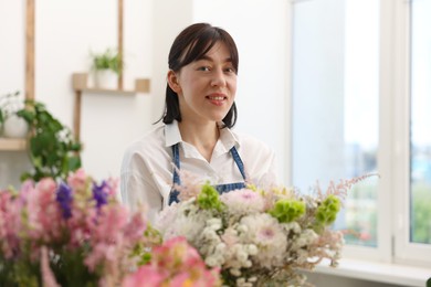 Photo of Florist with beautiful bouquet of flowers indoors