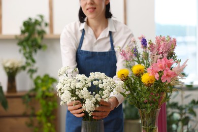 Photo of Florist with beautiful bouquet of flowers indoors, closeup