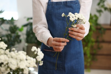 Photo of Florist with beautiful gypsophila flowers indoors, closeup