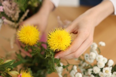 Photo of Florist making bouquet of flowers at table, closeup
