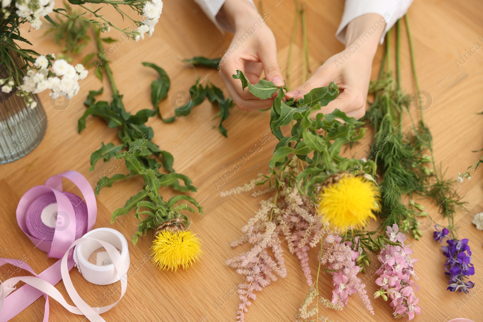 Florist making bouquet of flowers at wooden table, above view Photo of Florist making bouquet of flowers at wooden table, above view
