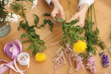 Photo of Florist making bouquet of flowers at wooden table, above view