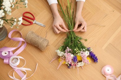 Photo of Florist making bouquet of flowers at wooden table, top view