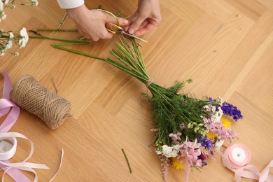 Photo of Florist making bouquet of flowers at wooden table, top view