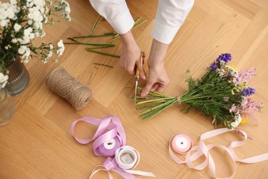 Photo of Florist making bouquet of flowers at wooden table, top view