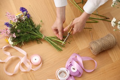 Photo of Florist making bouquet of flowers at wooden table, top view