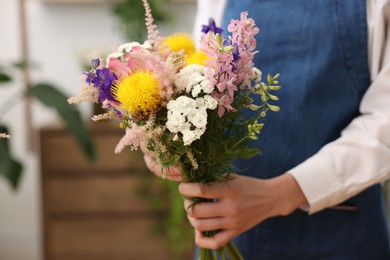 Photo of Florist with beautiful bouquet of flowers indoors, closeup