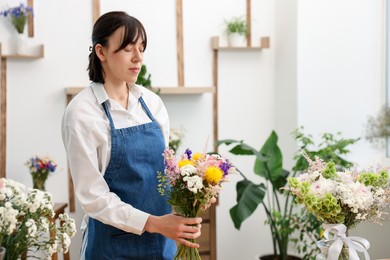Photo of Florist with beautiful bouquet of flowers indoors