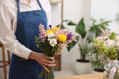 Photo of Florist with beautiful bouquet of flowers indoors, closeup