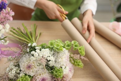 Photo of Florist making bouquet of flowers at wooden table, closeup