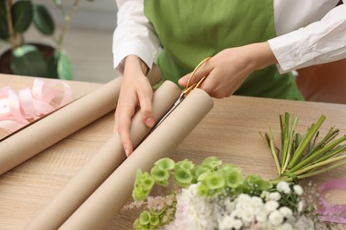 Photo of Florist making bouquet of flowers at wooden table, closeup