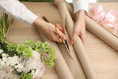 Photo of Florist making bouquet of flowers at wooden table, above view