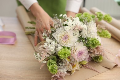 Photo of Florist making bouquet of flowers at wooden table, closeup