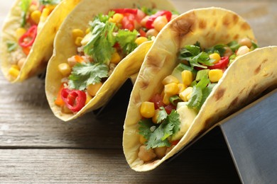 Photo of Tasty vegetarian tacos with chickpeas, corn and quinoa served on wooden table, closeup