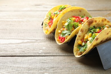 Photo of Tasty vegetarian tacos with chickpeas, corn and quinoa served on wooden table, closeup. Space for text