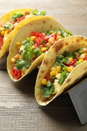 Photo of Tasty vegetarian tacos with chickpeas, corn and quinoa served on wooden table, closeup