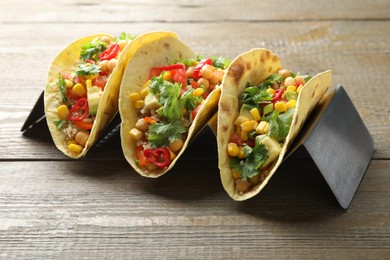 Photo of Tasty vegetarian tacos with chickpeas, corn and quinoa served on wooden table, closeup
