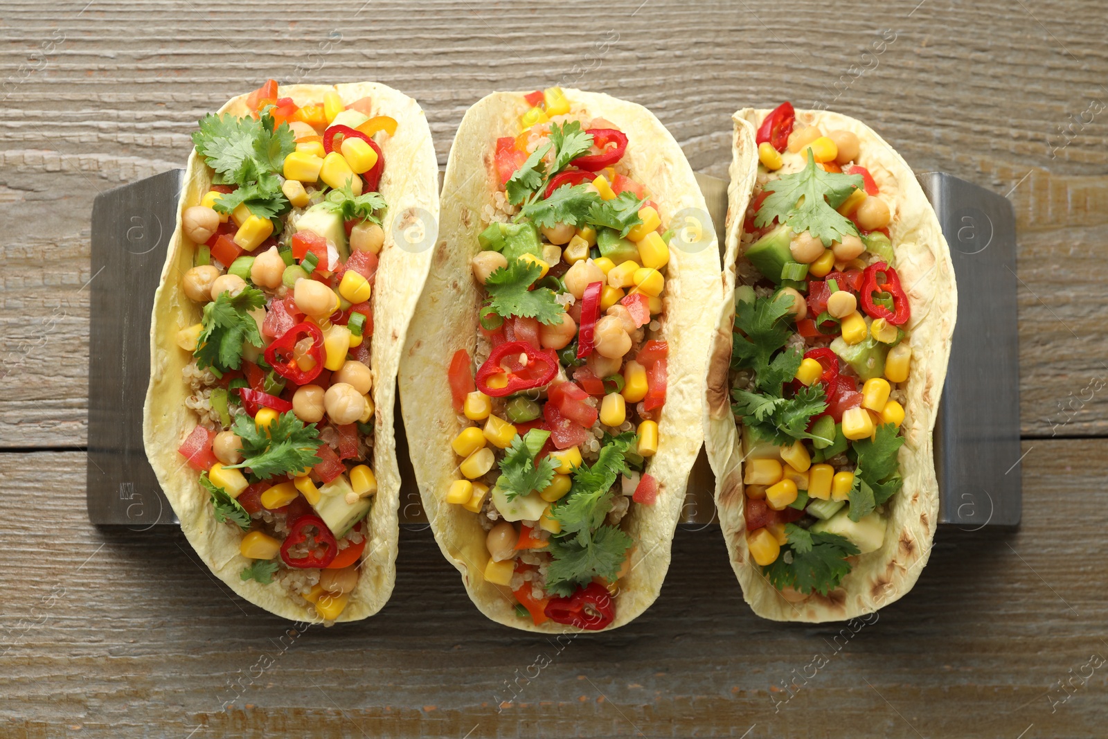 Photo of Tasty vegetarian tacos with chickpeas, corn and quinoa served on wooden table, top view