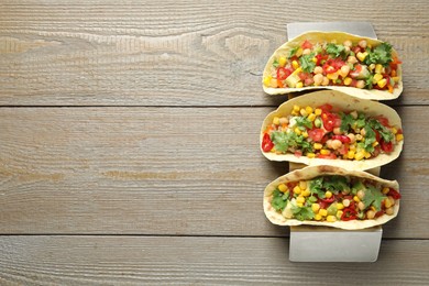 Photo of Tasty vegetarian tacos with chickpeas, corn and quinoa served on wooden table, top view. Space for text