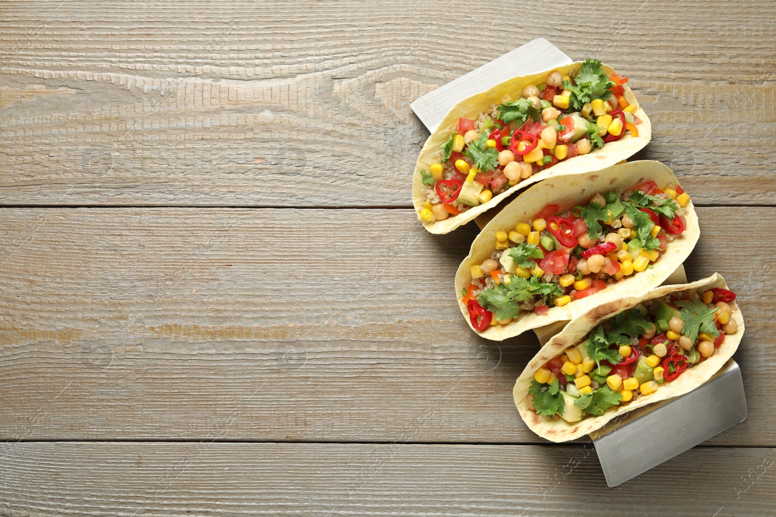 Photo of Tasty vegetarian tacos with chickpeas, corn and quinoa served on wooden table, top view. Space for text