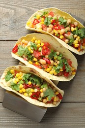Photo of Tasty vegetarian tacos with chickpeas, corn and quinoa served on wooden table, top view