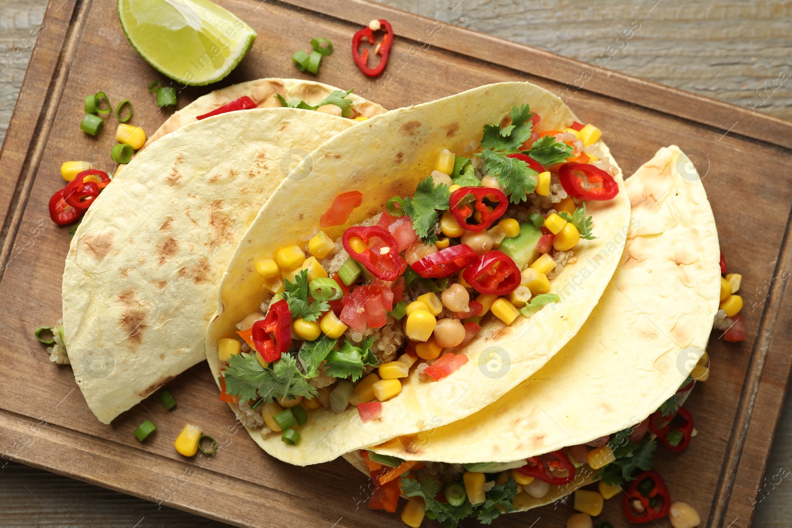 Photo of Tasty vegetarian tacos with chickpeas, corn and quinoa served on wooden table, top view