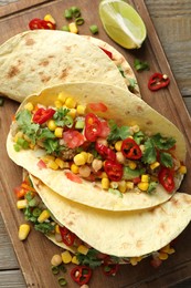 Photo of Tasty vegetarian tacos with chickpeas, corn and quinoa served on wooden table, top view