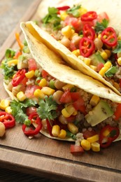 Photo of Tasty vegetarian tacos with chickpeas, corn and quinoa served on wooden table, closeup