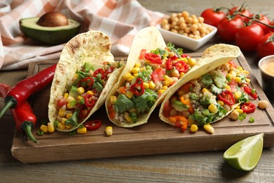 Photo of Tasty vegetarian tacos with chickpeas, corn and quinoa served on wooden table, closeup