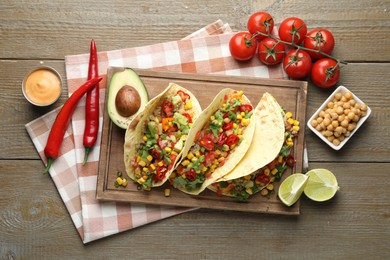Photo of Tasty vegetarian tacos with chickpeas, corn and quinoa served on wooden table, flat lay