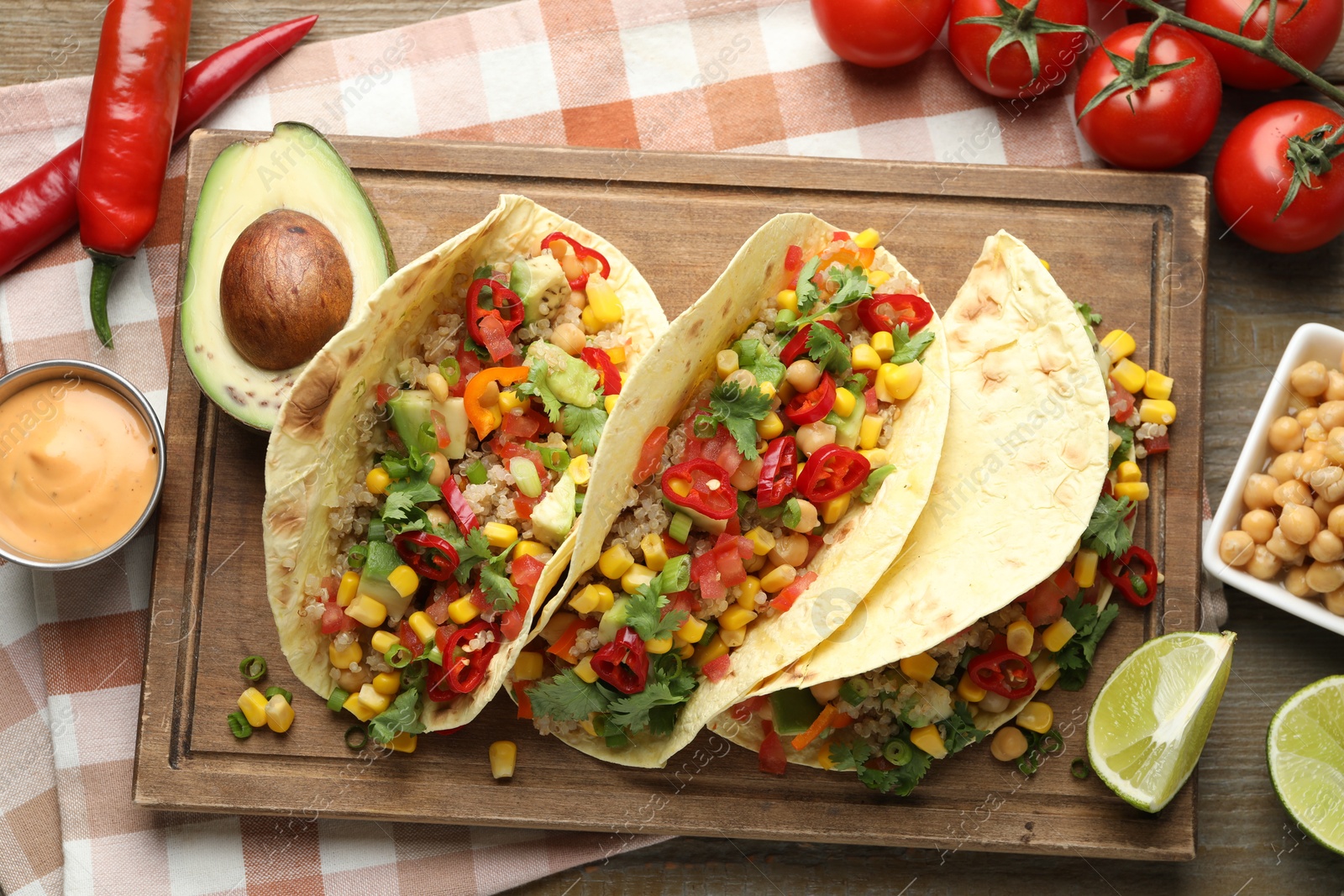 Photo of Tasty vegetarian tacos with chickpeas, corn and quinoa served on wooden table, flat lay