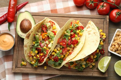 Photo of Tasty vegetarian tacos with chickpeas, corn and quinoa served on wooden table, flat lay