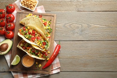 Photo of Tasty vegetarian tacos with chickpeas, corn and quinoa served on wooden table, flat lay. Space for text