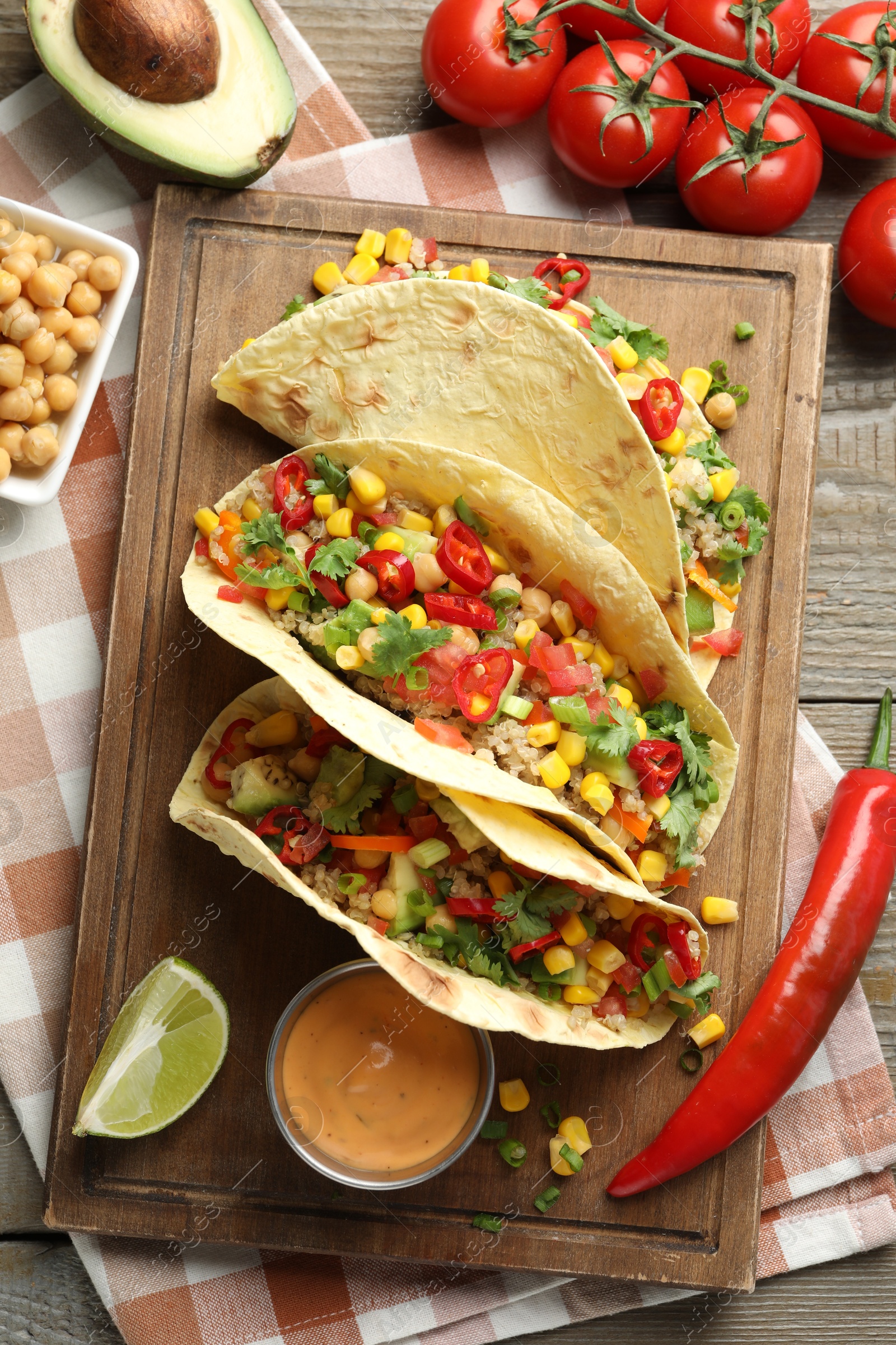 Photo of Tasty vegetarian tacos with chickpeas, corn and quinoa served on wooden table, flat lay