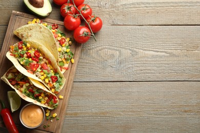 Photo of Tasty vegetarian tacos with chickpeas, corn and quinoa served on wooden table, flat lay. Space for text