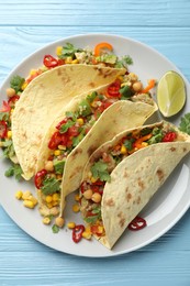 Photo of Tasty vegetarian tacos with chickpeas, corn and quinoa served on light blue wooden table, top view