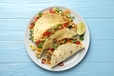 Photo of Tasty vegetarian tacos with chickpeas, corn and quinoa served on light blue wooden table, top view
