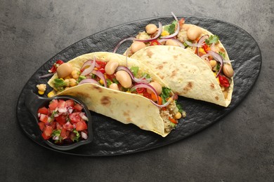 Photo of Tasty vegetarian tacos with beans and quinoa served on grey table, top view