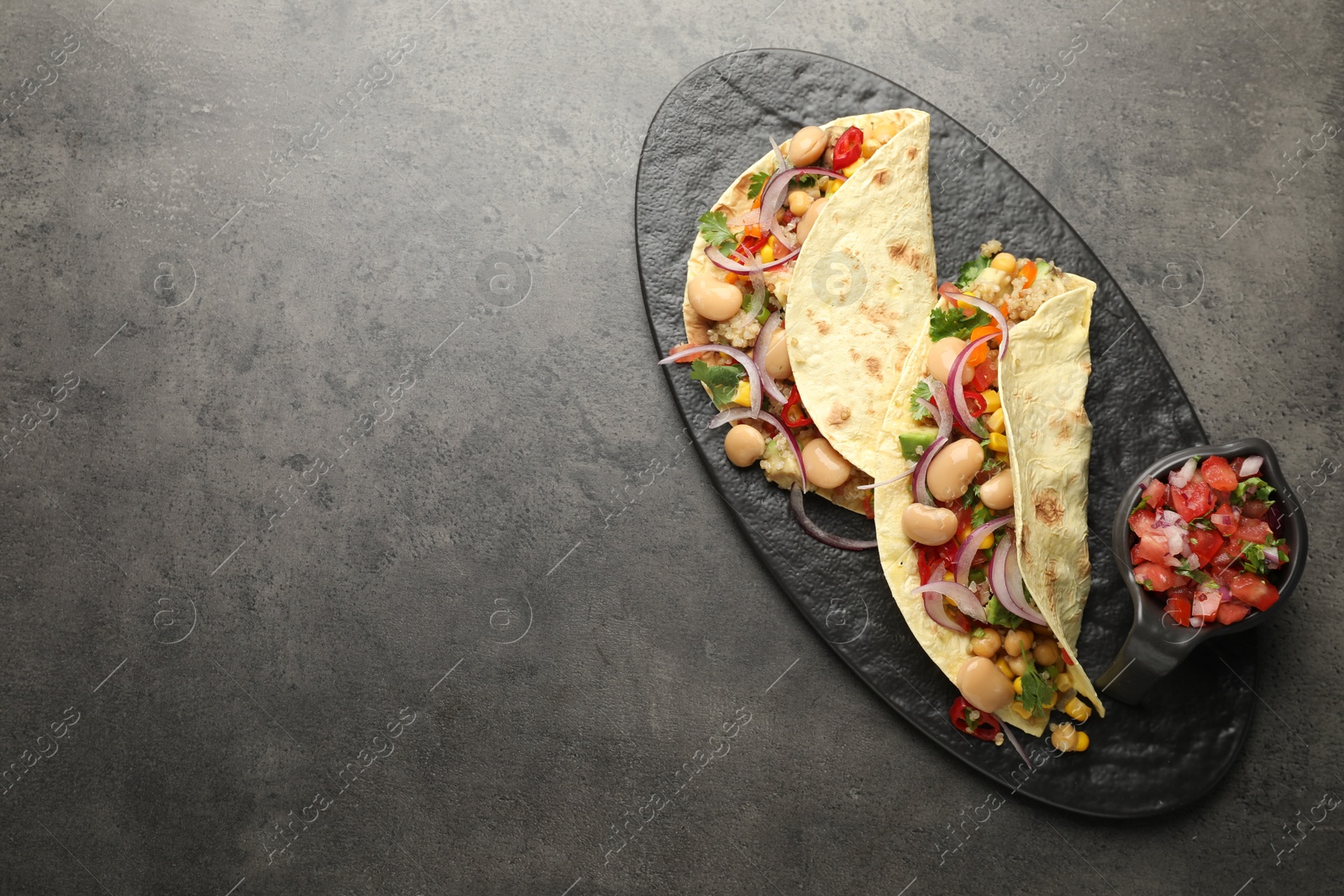 Photo of Tasty vegetarian tacos with beans and quinoa served on grey table, top view. Space for text